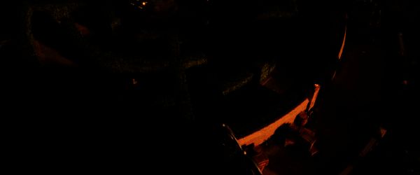 主角躲在墙角观察巡逻士兵，远处灯光闪烁营造紧张氛围