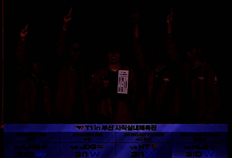 T1战队成员庆祝胜利瞬间，背景为LCK赛场灯光璀璨