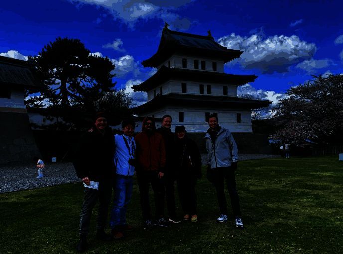 团队成员与当地长者亲切交流，背景为传统木屋内部