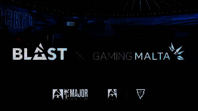 BLAST与马耳他政府签约仪式现场，双方代表握手合影，背景为马耳他标志性建筑与电竞大屏