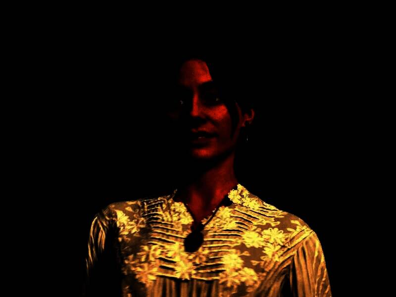 《四海兄弟：故乡》女性角色正面特写，身穿复古风衣，眼神犀利，背景为上世纪西西里街道