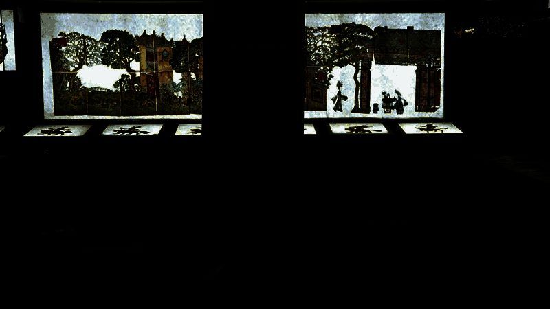 张华州手持皮影雕刻工具专注工作，桌上摆放着未完成的皮影角色