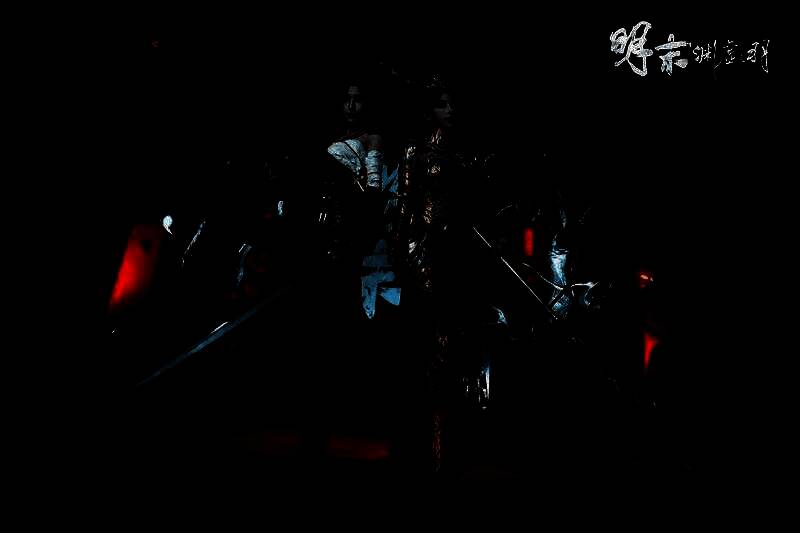 两位Coser并肩站立，分别还原‘婉若游龙’与‘绣袍’外观，背景为展台灯光，现场人潮涌动