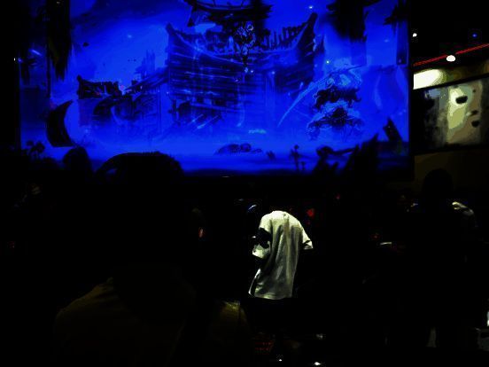 大屏幕显示游戏战斗画面，角色高速移动斩击敌人，特效炸裂