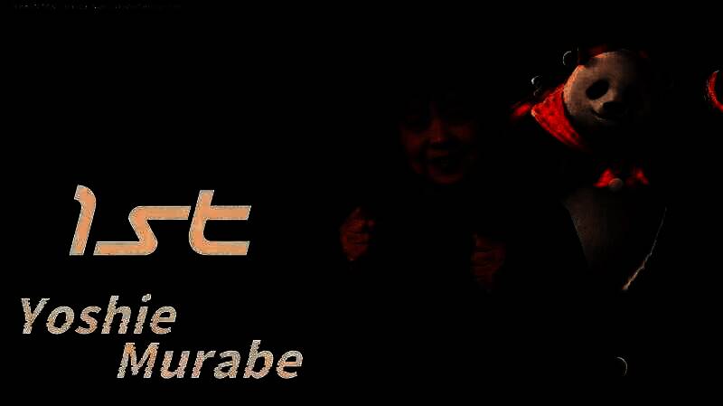 73岁冠军村部良江高举奖杯，面带笑容，身旁工作人员鼓掌祝贺，背景为赛事舞台