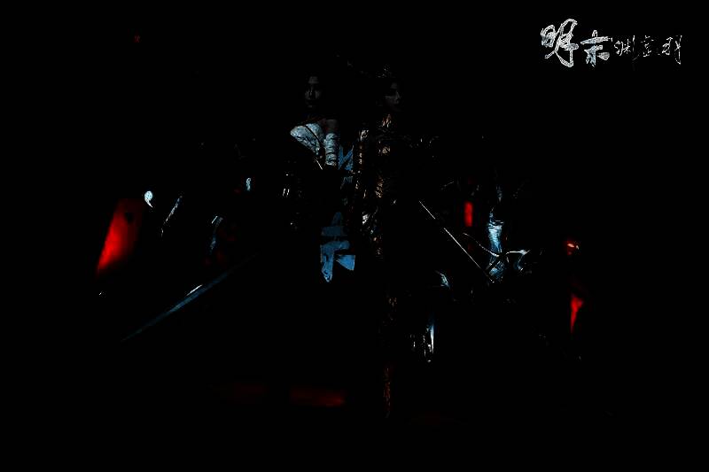 Coser身着《明末：渊虚之羽》豪华版服饰【婉若游龙】与【绣袍】在展台前摆出战斗姿态，周围玩家纷纷拍照