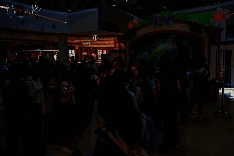 玩家正在参与互动游戏，工作人员在一旁指导，桌上摆放着各类奖品