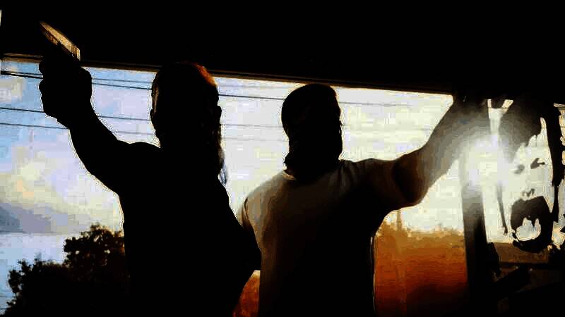 游戏界面模拟图显示多名玩家角色聚集在城市中心广场，部分人持武器对峙，周围车辆停靠，天空有直升机盘旋，呈现紧张对战氛围