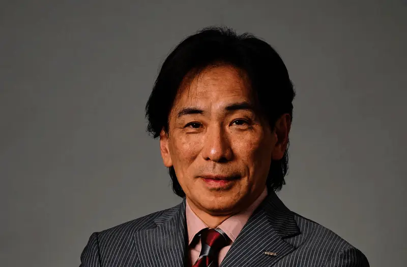 世嘉总裁内海州史在公开场合发言，背景为世嘉经典游戏角色与LOGO组成的视觉墙