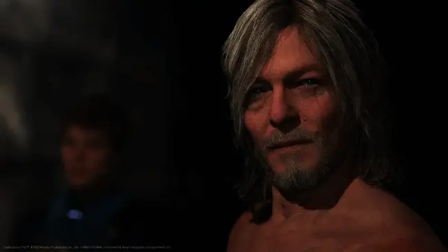 小岛秀夫在活动现场发表演讲，神情激动，背景为《死亡搁浅2》巨幅宣传画面