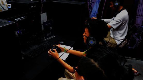 一位年轻玩家在家长指导下体验游戏，两人共同注视屏幕，笑容满面