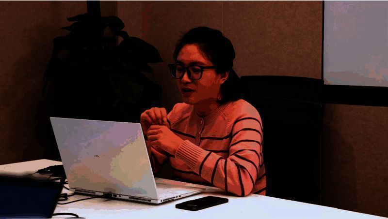 测试人员正在多设备上验证AI功能，女性测试工程师专注记录交互细节，身旁摆放着标注问题的测试报告