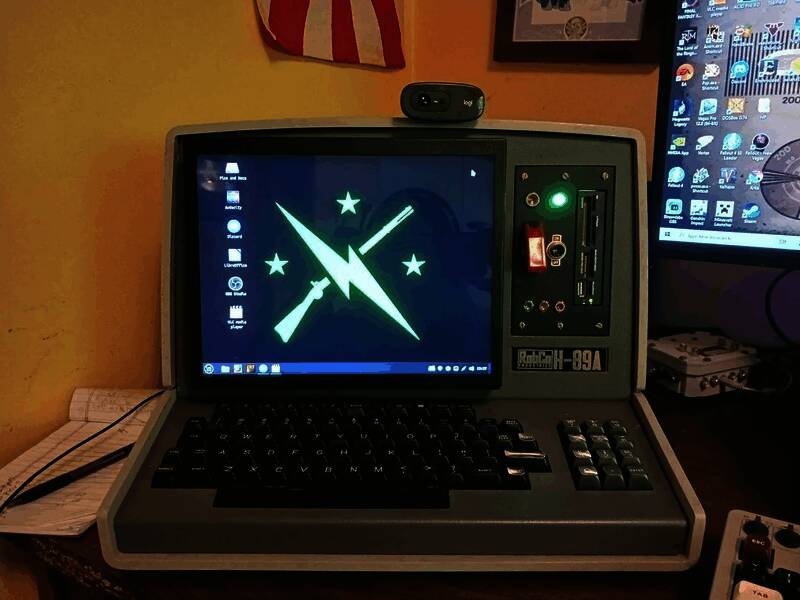 一台高度还原《辐射》游戏中终端样式的实体设备，外壳为老式电脑改装，贴有义勇军标志和复古核能风格贴纸