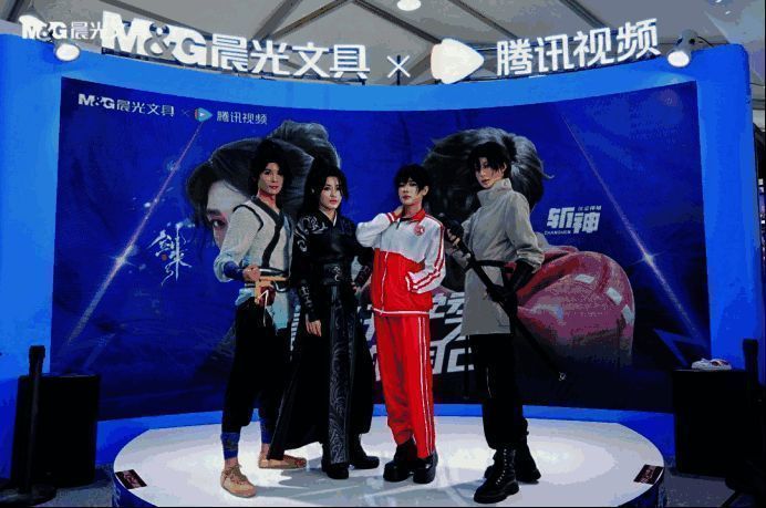 晨光展台中央布置《剑来》水墨风主视觉，观众手持联名文具在角色立牌前拍照留念