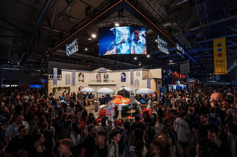 科隆游戏展现场人潮涌动，中国展台前玩家排队体验，背景可见《无限暖暖》与《恋与深空》的大型立绘