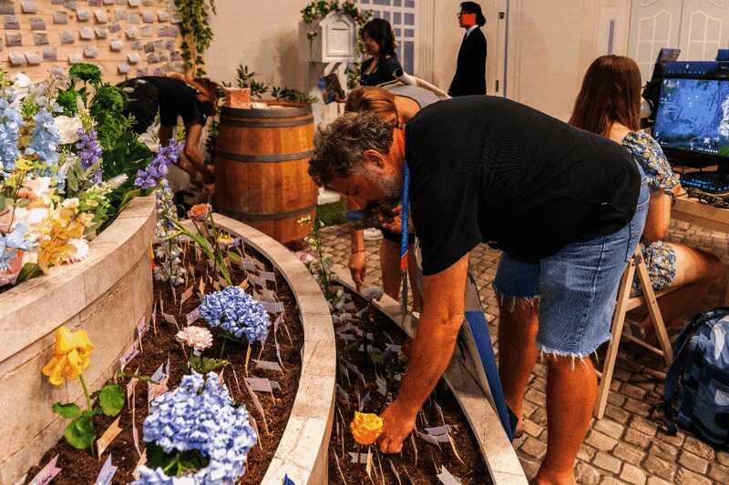 《无限暖暖》展区内玩家正在参与‘种植花卉’互动，屏幕上显示花朵生长动画，周围布置着梦幻花园装饰