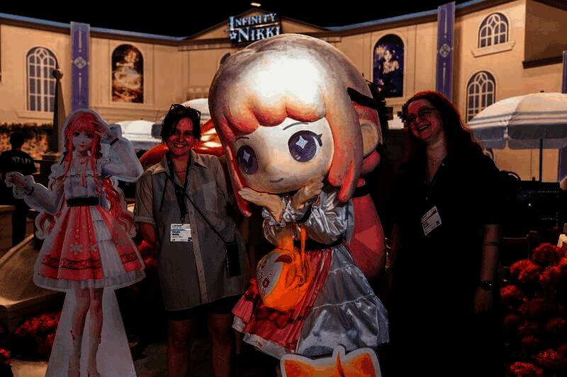 德国玩家在《无限暖暖》展台前与大熊猫主题角色立牌合影，脸上洋溢着笑容