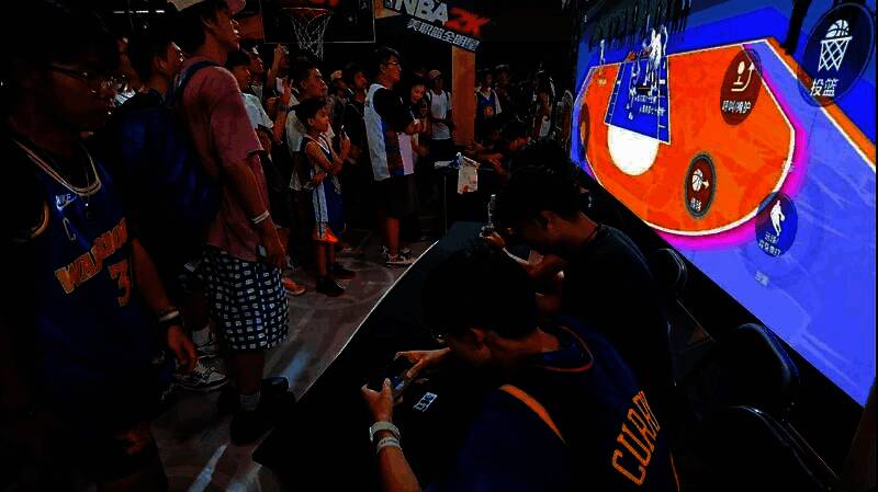 一名玩家戴着巨型篮球手套尝试投篮，动作滑稽，周围观众大笑