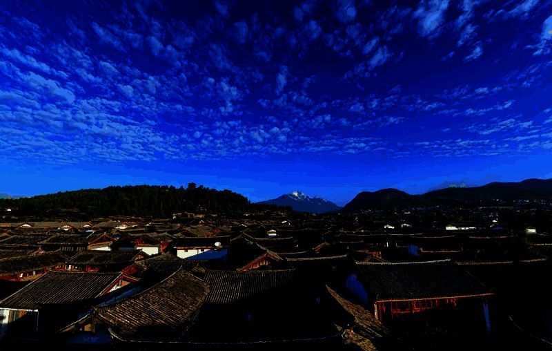 丽江古城夜景实景图，灯火辉煌，小桥流水，游客穿梭其中，展现千年古城的繁华与静谧