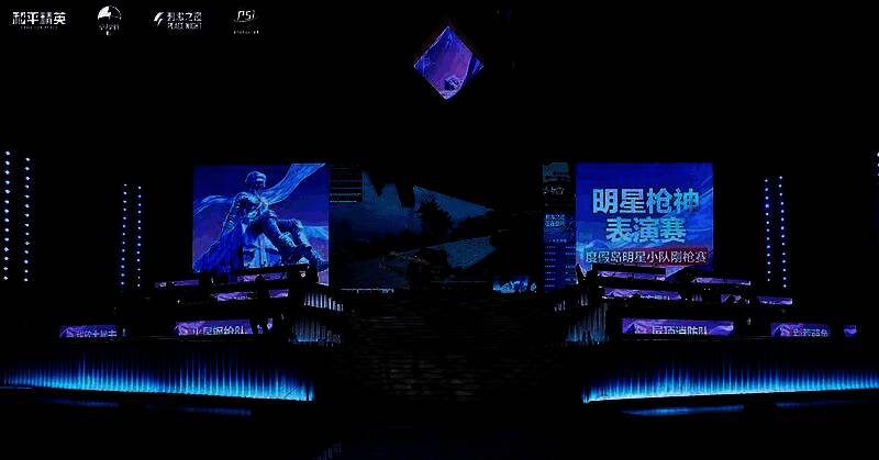 明星们佩戴耳机专注操作，大屏幕显示游戏内激烈对战画面，现场气氛紧张热烈