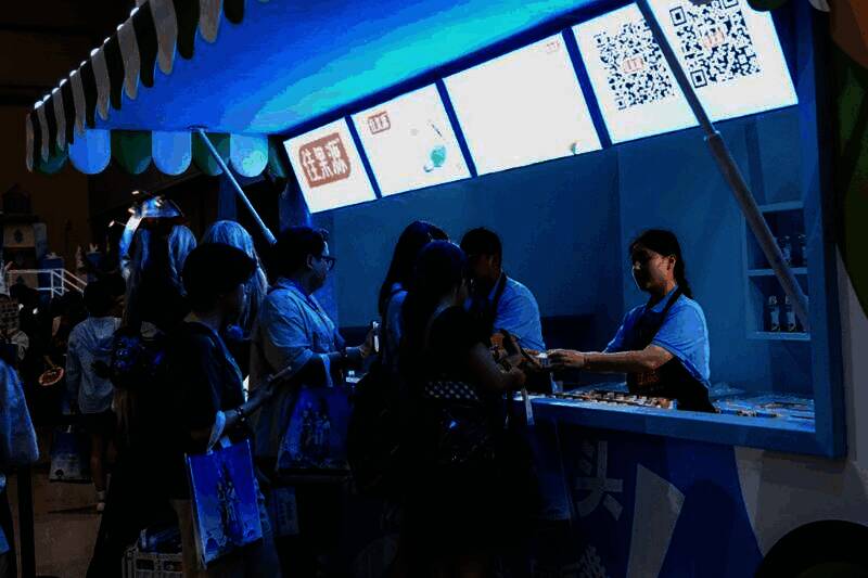 玩家在必胜客联动摊位前排队等候，背景是FGO主题装饰与角色立牌