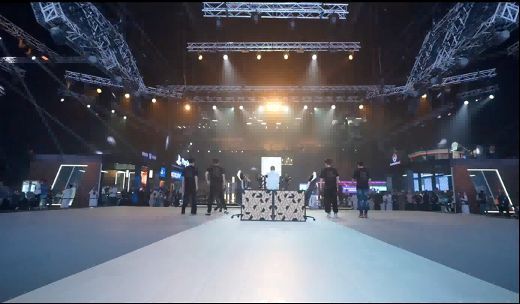 《异人之下》表演赛现场，两名选手专注对战，大屏幕上显示激烈格斗画面，观众席人头攒动