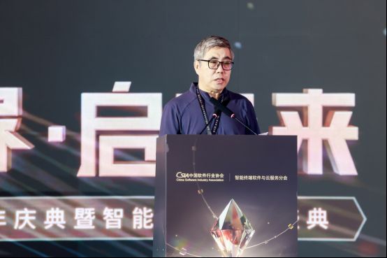 陈宝国先生在大会舞台上发表演讲，神情专注，背景为智能终端联盟LOGO