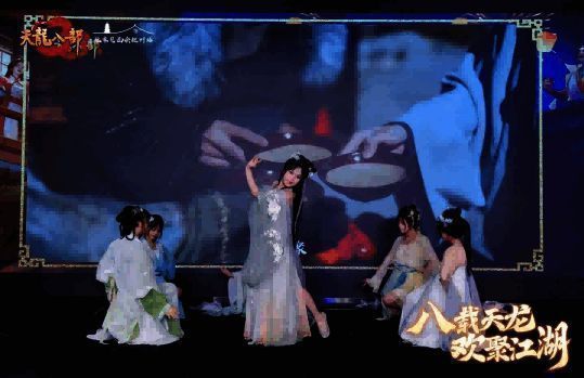 舞团成员身穿桃花主题服饰，在舞台上翩翩起舞，背景灯光营造出梦幻般的桃林景象