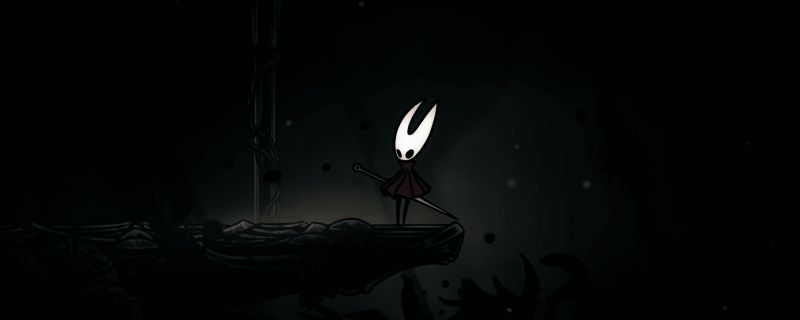 《空洞骑士：丝之歌》游戏内场景，角色在昏暗洞穴中战斗，背景充满神秘氛围