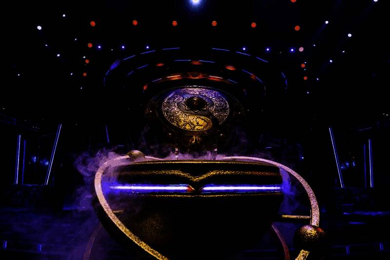 观众席上粉丝举着支持战队的旗帜，神情投入地观看比赛直播