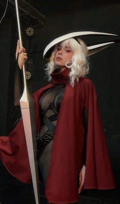 Coser alexibodler扮演的大黄蜂正面照，身穿红黑配色披风，手持骨钉，背景暗色调突出角色神秘感