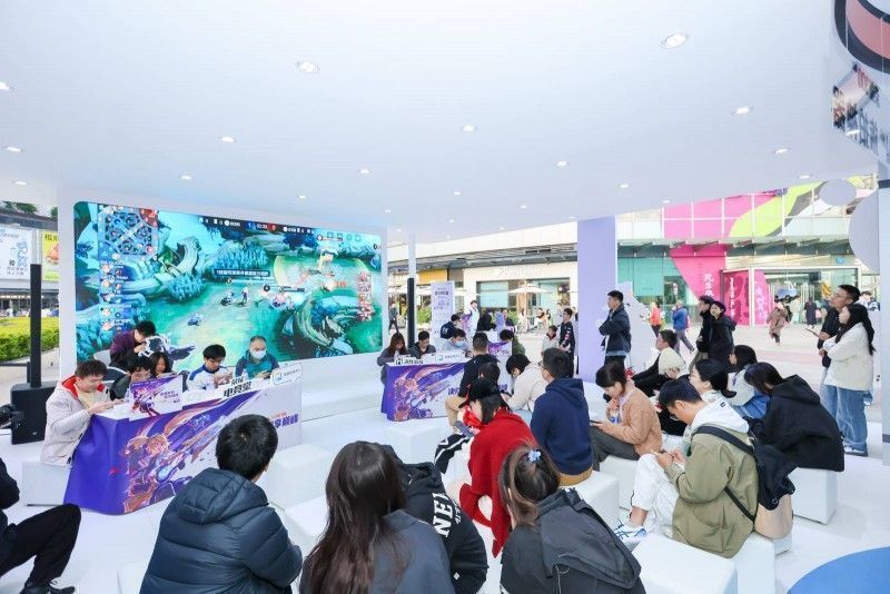 两支战队正在进行《决胜巅峰》5V5对战，大屏实时显示比赛画面，观众围观点燃气氛