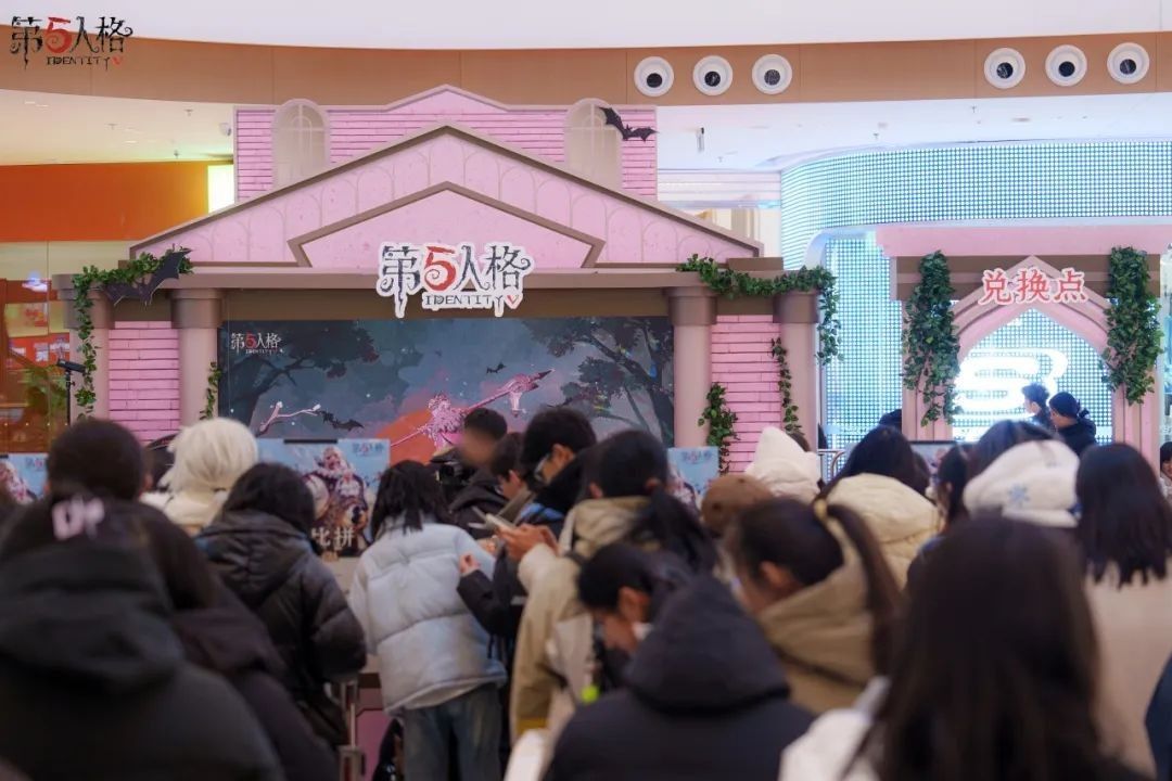 COSER扮演的画家手持画笔站在展台前，周围玩家围拢拍照，背景是冬至主题的灯饰与海报