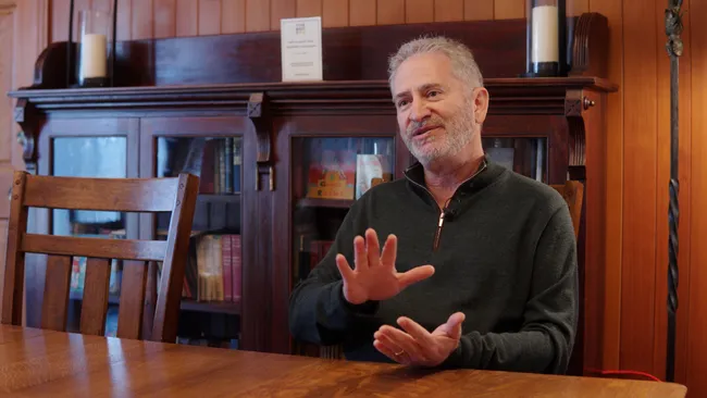 Mike Morhaime公开信截图，神情凝重地宣布公司裁员决定，背景为Dreamhaven公司LOGO