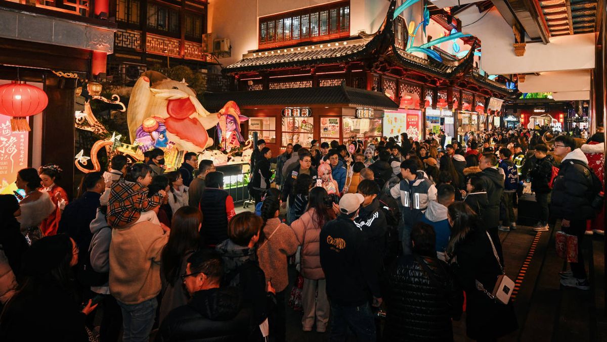 夜幕下的豫园主灯区，巨型蛇形灯饰蜿蜒盘旋，周围环绕着游戏角色剪影，气势恢宏