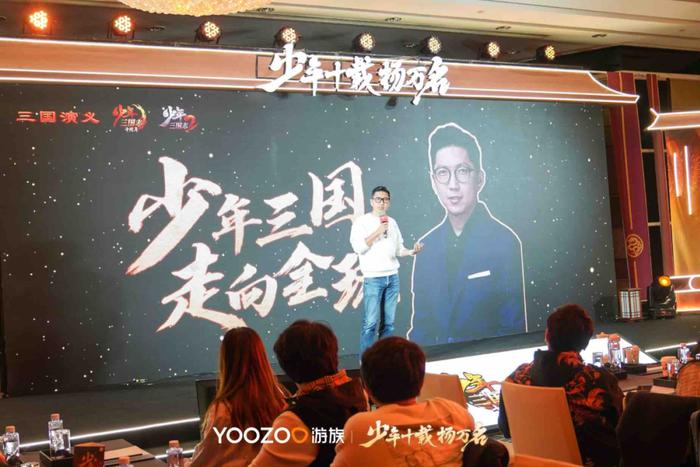 游族网络CEO陈芳在十周年庆典上发表演讲，神情专注，背景为《少年三国志》系列发展历程时间轴