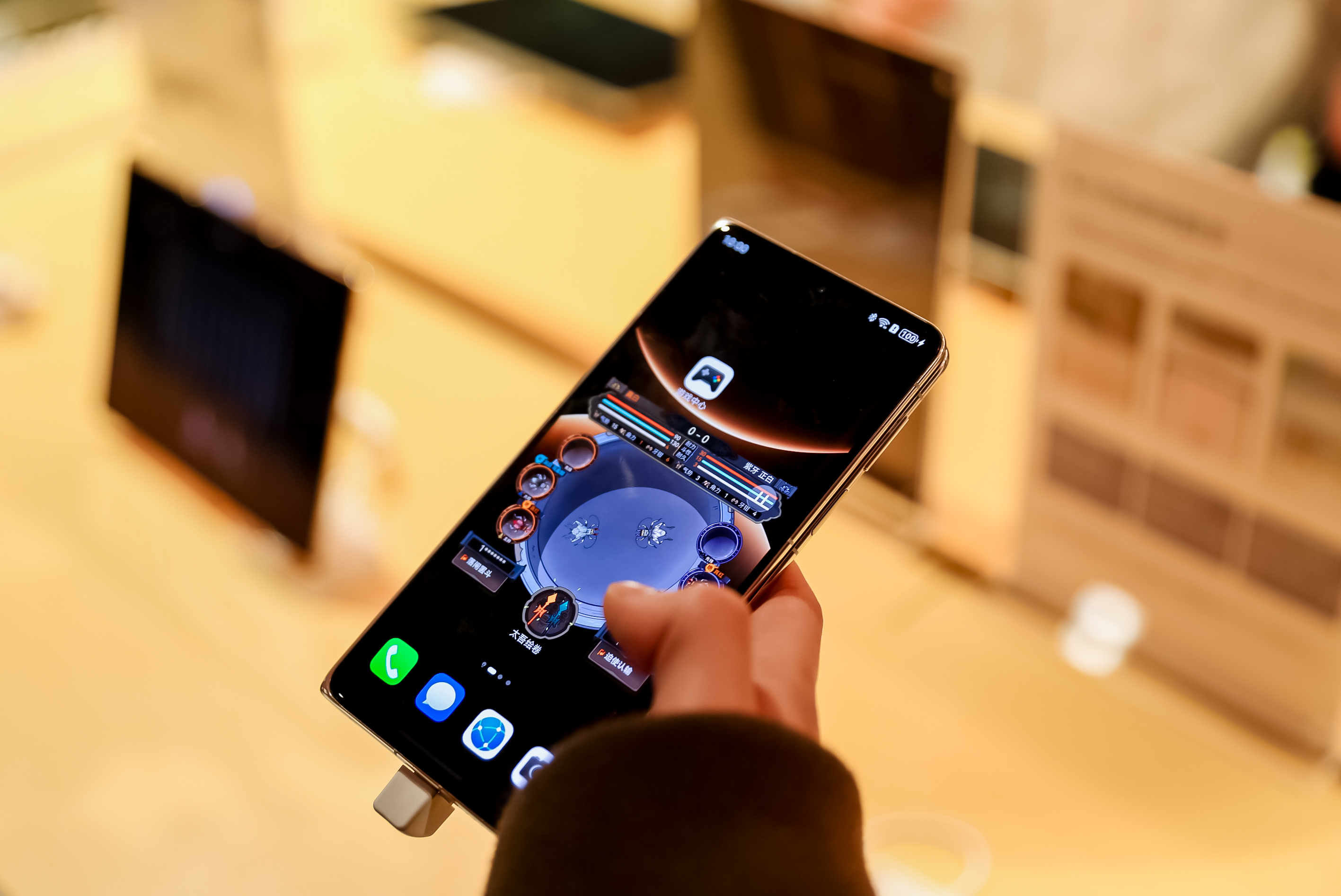 鸿蒙体验区特写：一名玩家正用华为MatePad进行游戏，画面同步显示在旁边的华为MateBook屏幕上，两台设备间浮现蓝色光效连接动效，桌面摆放‘碰一碰分享存档’指引卡