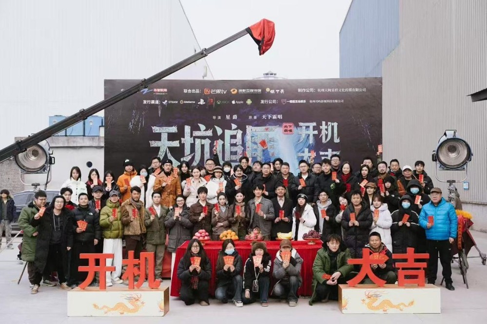 片场工作照：演员刘宴侨身穿复古工装服，在巨型天坑布景前与动作指导沟通肢体语言细节，背景可见实时渲染的3D岩层投影