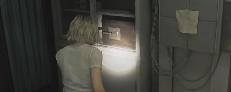 《生化危机9：安魂曲》疗养院检查室内景：昏暗灯光下，锈蚀金属检查台旁立着一个带数字转盘的复古保险箱，箱体表面有细微划痕与干涸血迹