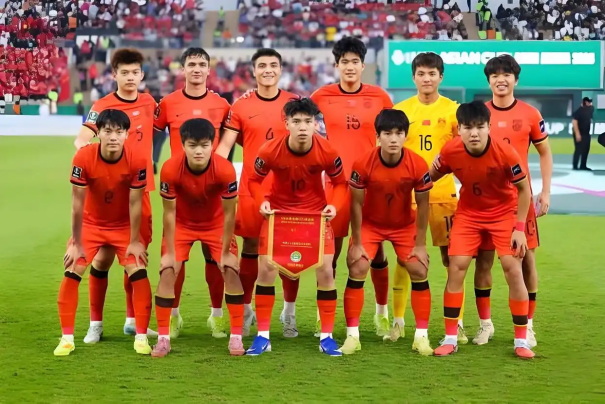 U23亚洲杯决赛现场全景图，中国队球员神情坚毅列队致意，背景大屏显示0-4比分与日本国旗，现场观众席座无虚席