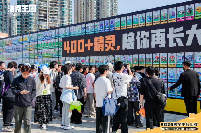 广州塔东广场实景布置图：巨型迪莫与鸭吉吉气模分列两侧，中央为复古魔法风格图鉴墙，多名玩家正仰头辨认精灵图案