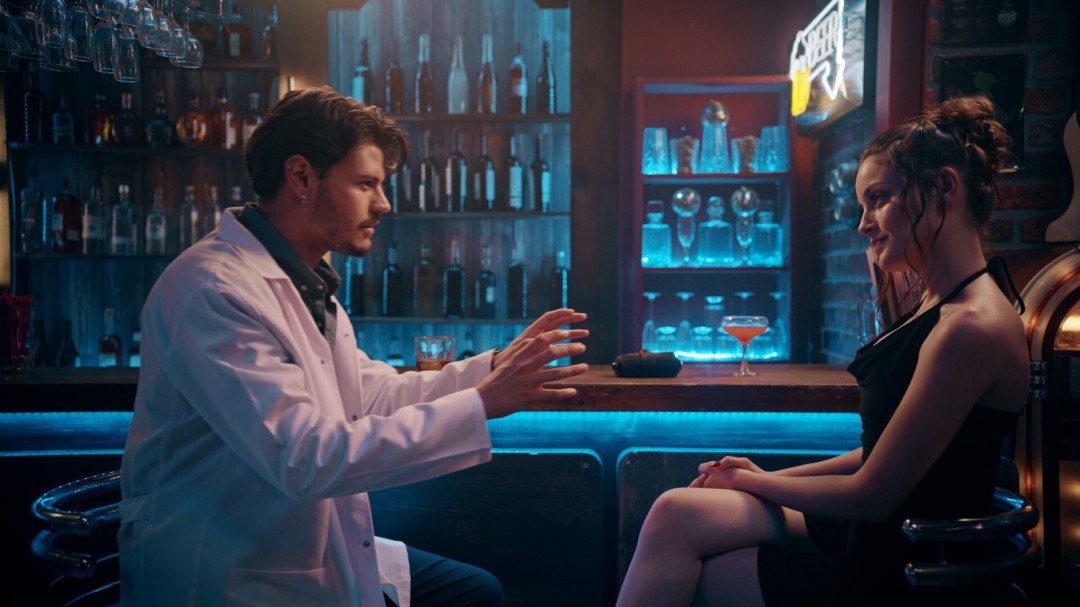 密闭室内场景：库泰俯身查看老旧笔记本，页面写满潦草符号与‘她不是人类’字样，桌上散落骰子与一张撕去半边的照片