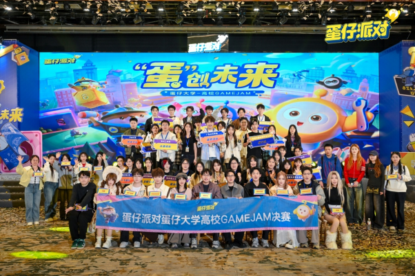 首届蛋仔大学高校GameJam线下总决赛大合影：19支高校战队身着各校文化衫，手持蛋仔主题手幅，在郑州赛场背景板前笑容灿烂，现场氛围热烈欢腾